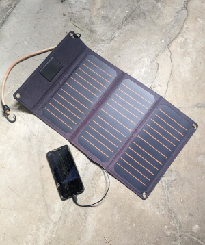 a cellphone with a broken screen is lying on a dirty concrete floor next to a solar charger